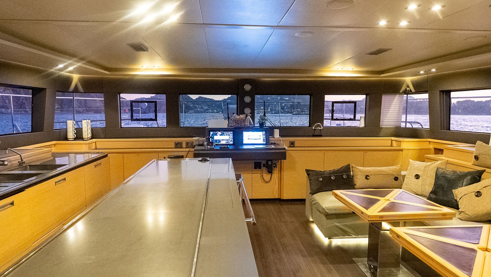 Luxurious yacht interior with dining area, plush seating, and panoramic windows showcasing a sea view.
