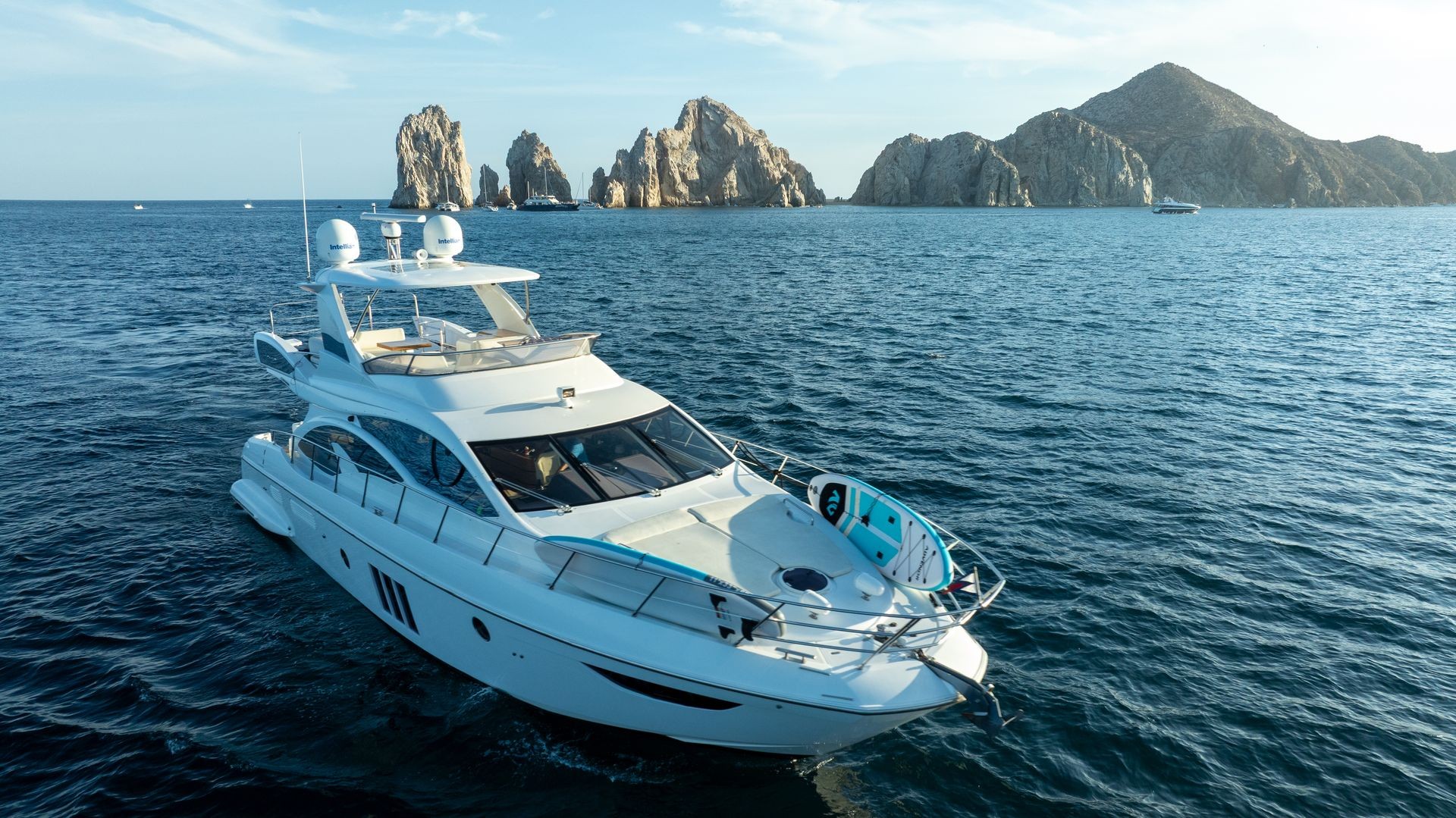 Luxury yacht on the sea with rocky cliffs in the background under a clear sky.