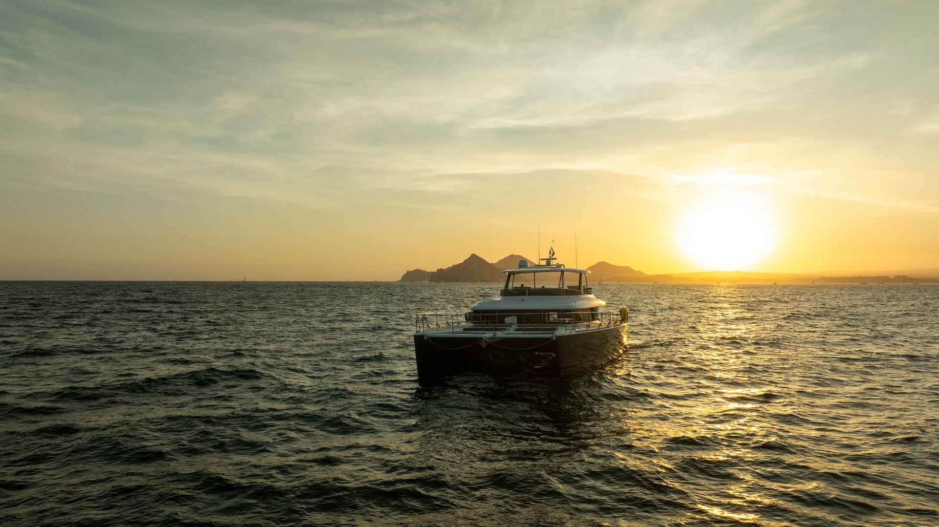 Boat on the ocean during a sunset with distant mountains visible.