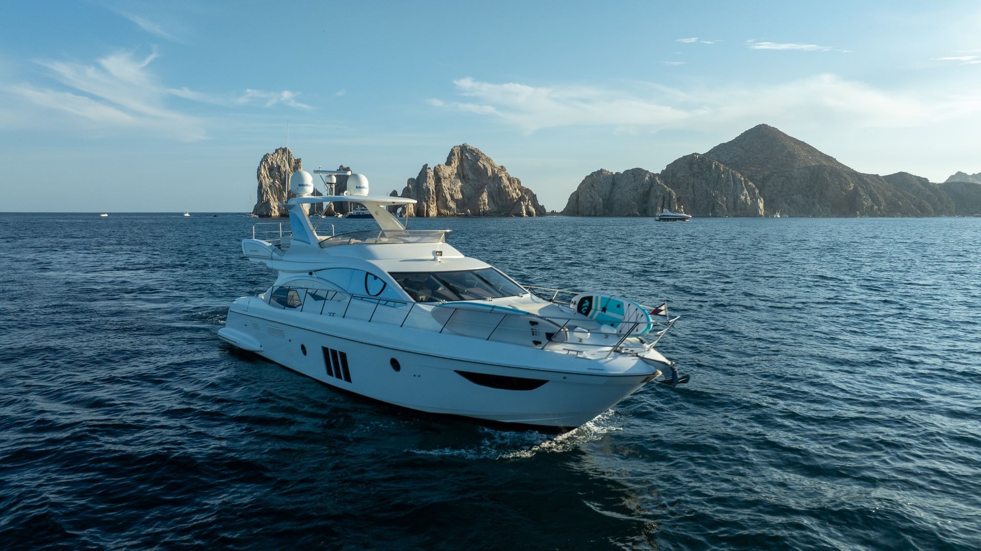 Luxury yacht sailing near rocky cliffs on a sunny day.