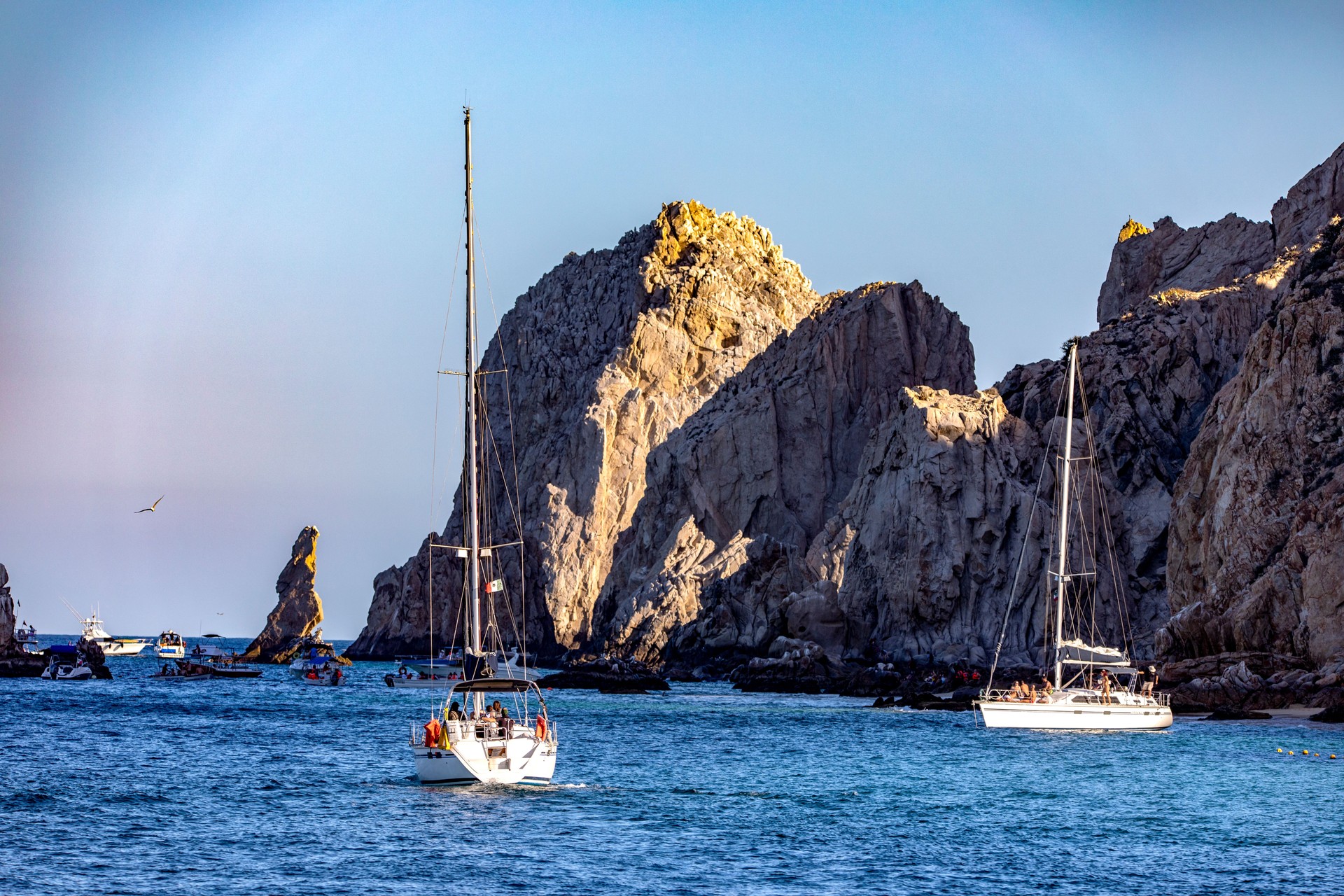 Boats sailing towards Cabo San Lucas Arch and Love Beach in the Sea of Cortez and the Pacific Ocean off the coast of the state of Baja California Sur of Mexico.